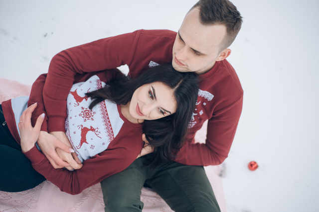 loving couple sitting in the woods in a red sweaters